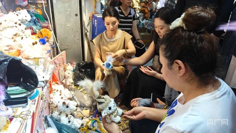 観光客の注文に合わせて羊のぬいぐるみを飾り付ける店主（撮影・郭璁悦）。